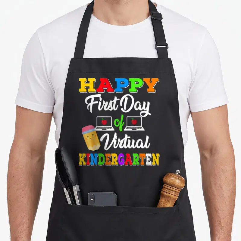 Virtual teaching apron - Stacked text HAPPY First Day of Virtual KINDERGARTEN with cartoon pencil and two laptops — shown on a black cotton canvas apron against a white background
