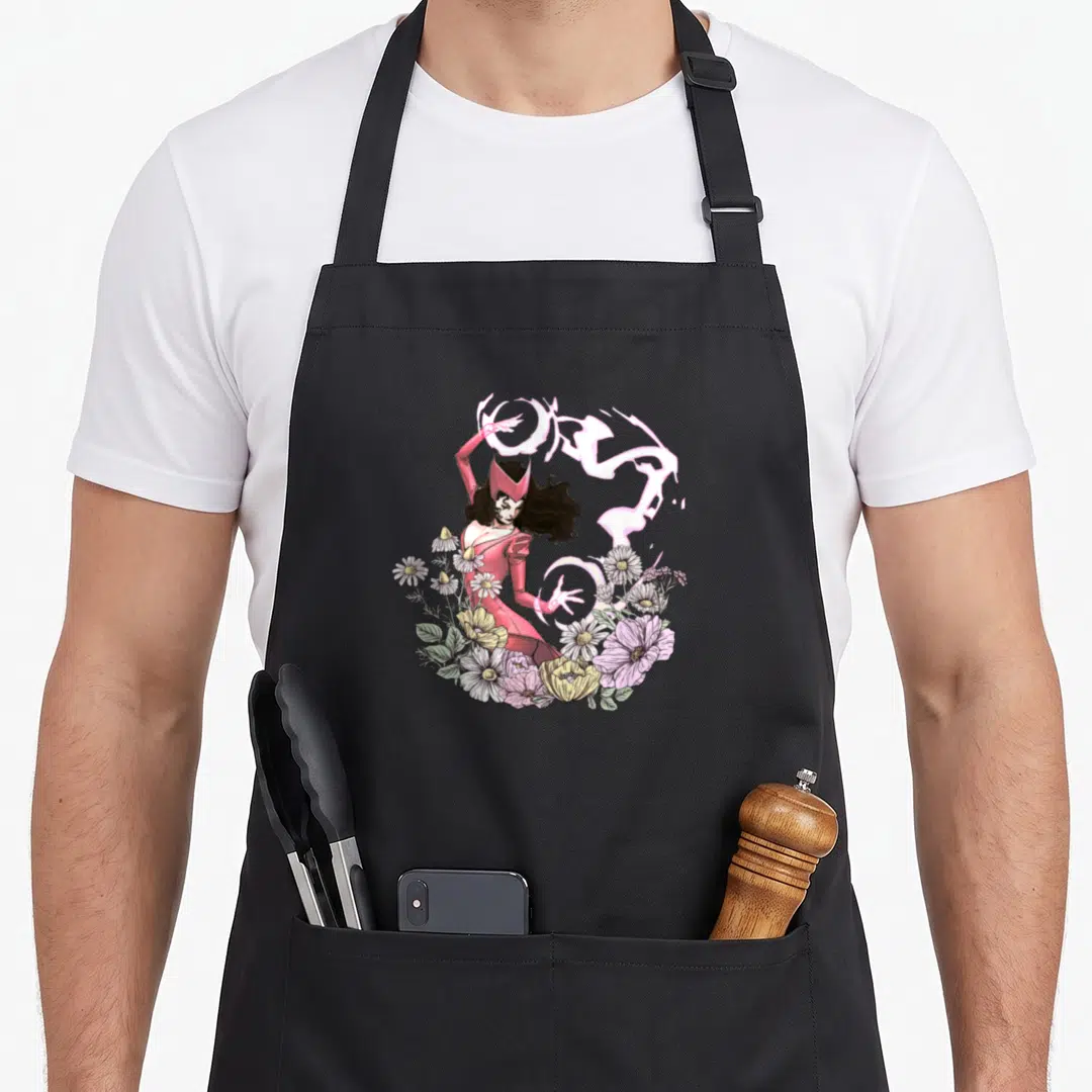 Funny floral spring apron - Scarlet Witch in pink dress surrounded by white daisies and swirling pink magic energy — shown on a black cotton canvas apron against a white background