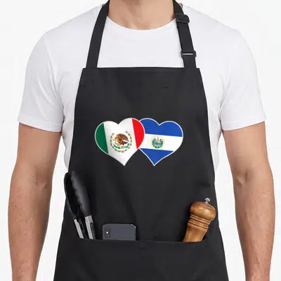 Mexican salvadorian el cook apron - Two overlapping heart-shaped Mexican and Salvadorian flags in green, white, red — shown on a black cotton canvas apron against a white background