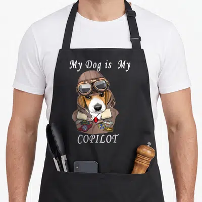 Dog chef and co aprons - Beagle in brown aviator helmet and goggles with patches reading LEADER ACE 1 COPILOT — shown on a black cotton canvas apron against a white background