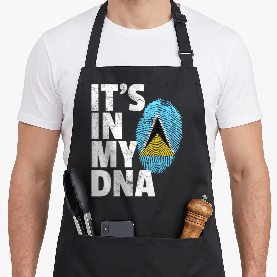 Saint country apron - IT'S IN MY DNA text beside Saint Lucia flag fingerprint in blue yellow black white — shown on a black cotton canvas apron against a white background