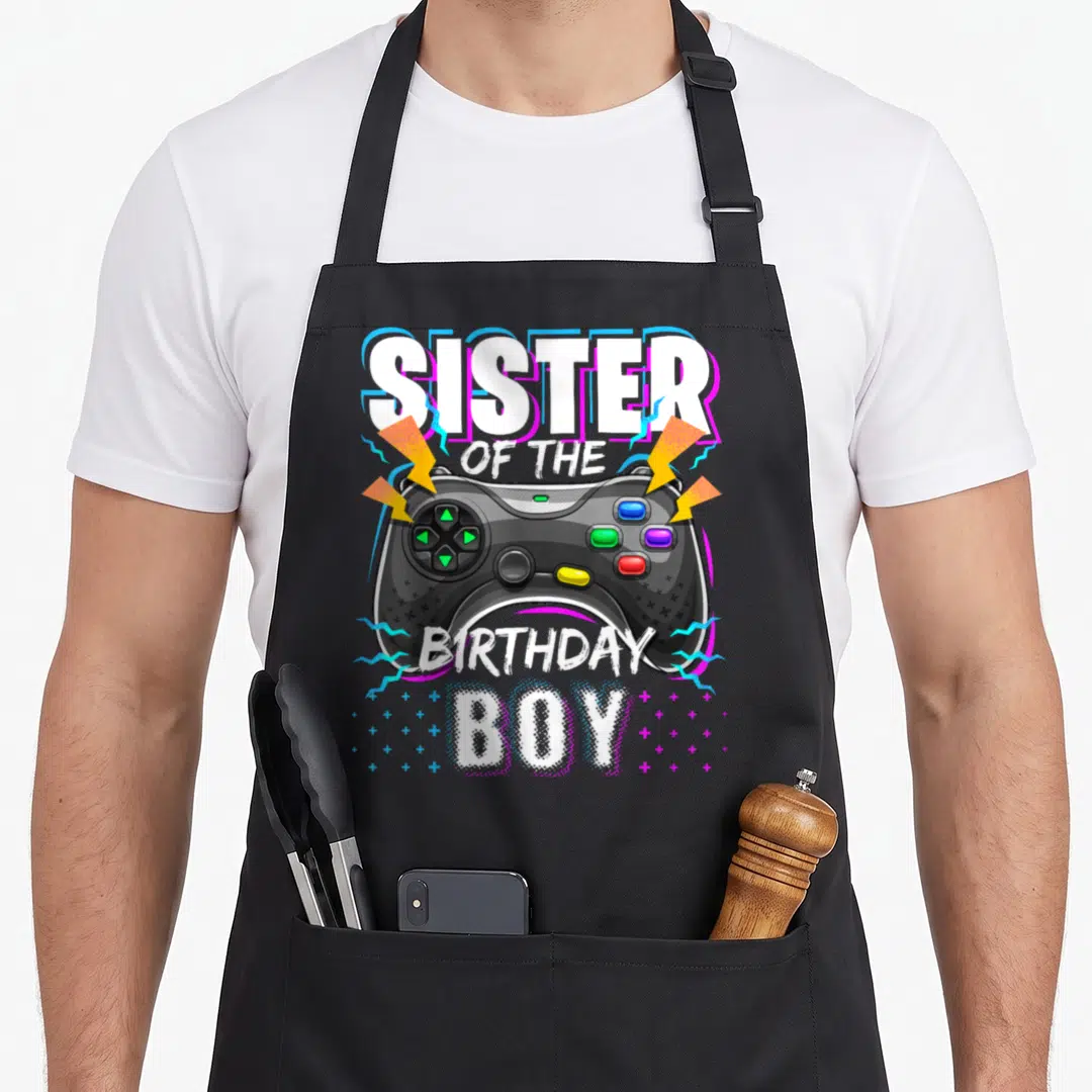 Sister birthday video game apron - Cartoon game controller with lightning bolts and sister of the birthday boy text — shown on a black cotton canvas apron against a white background