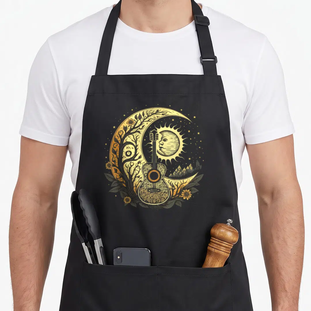 Acoustic cottagecore apron - Line art guitar inside crescent moon with sun face, sunflowers, mountains, and stars — shown on a black cotton canvas apron against a white background