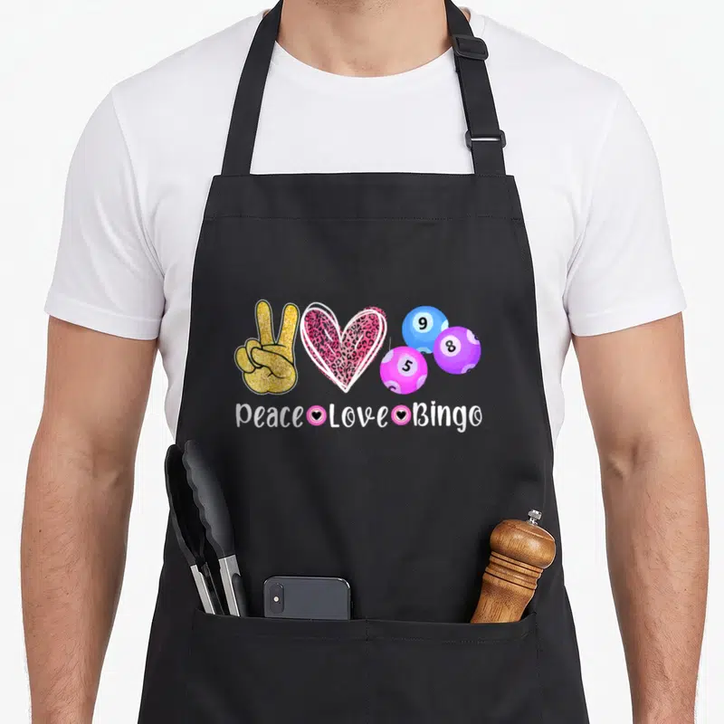 Peace bingo apron - Gold peace hand, leopard heart, three colored bingo balls, and white text reading Peace Love Bingo — shown on a black cotton canvas apron against a white background
