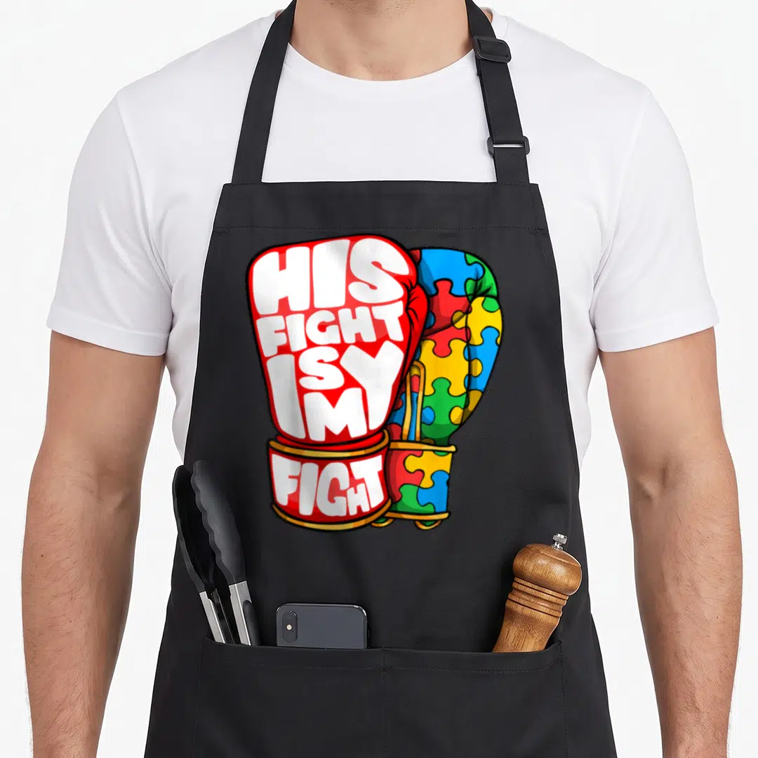 His autism dad apron - Two boxing gloves, one red with text, one with colorful puzzle pattern — shown on a black cotton canvas apron against a white background