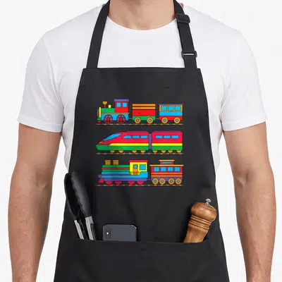 Railway steam locomotive apron - Three colorful cartoon trains stacked vertically on brown tracks in red, blue, yellow — shown on a black cotton canvas apron against a white background