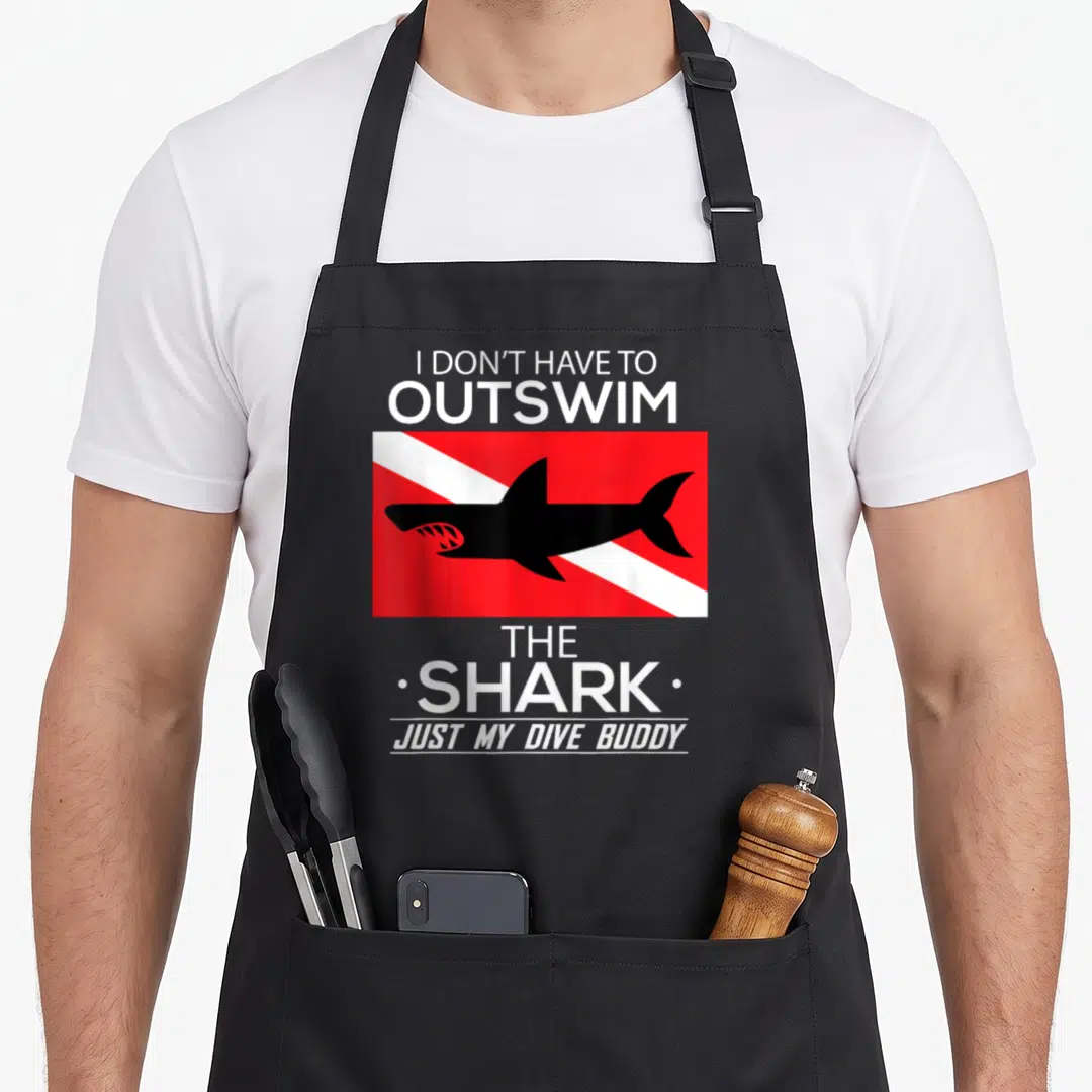 Swim buddy aprons - Black shark in red box with white stripe and quote about dive buddy — shown on a black cotton canvas apron against a white background