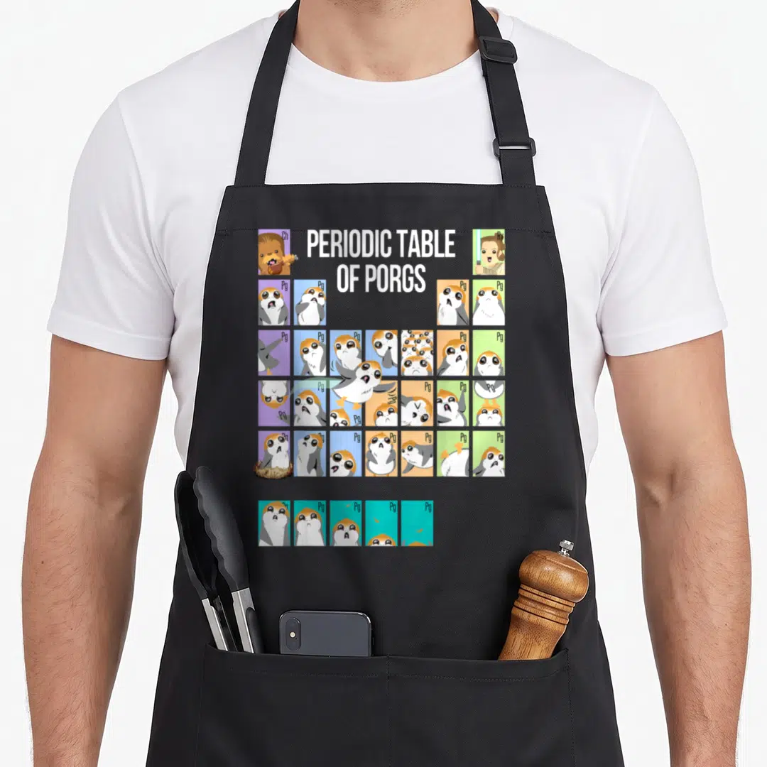Porg table apron - Cartoon Porgs in colored squares mimicking a periodic table with symbols Ch, Ry, and Pg — shown on a black cotton canvas apron against a white background