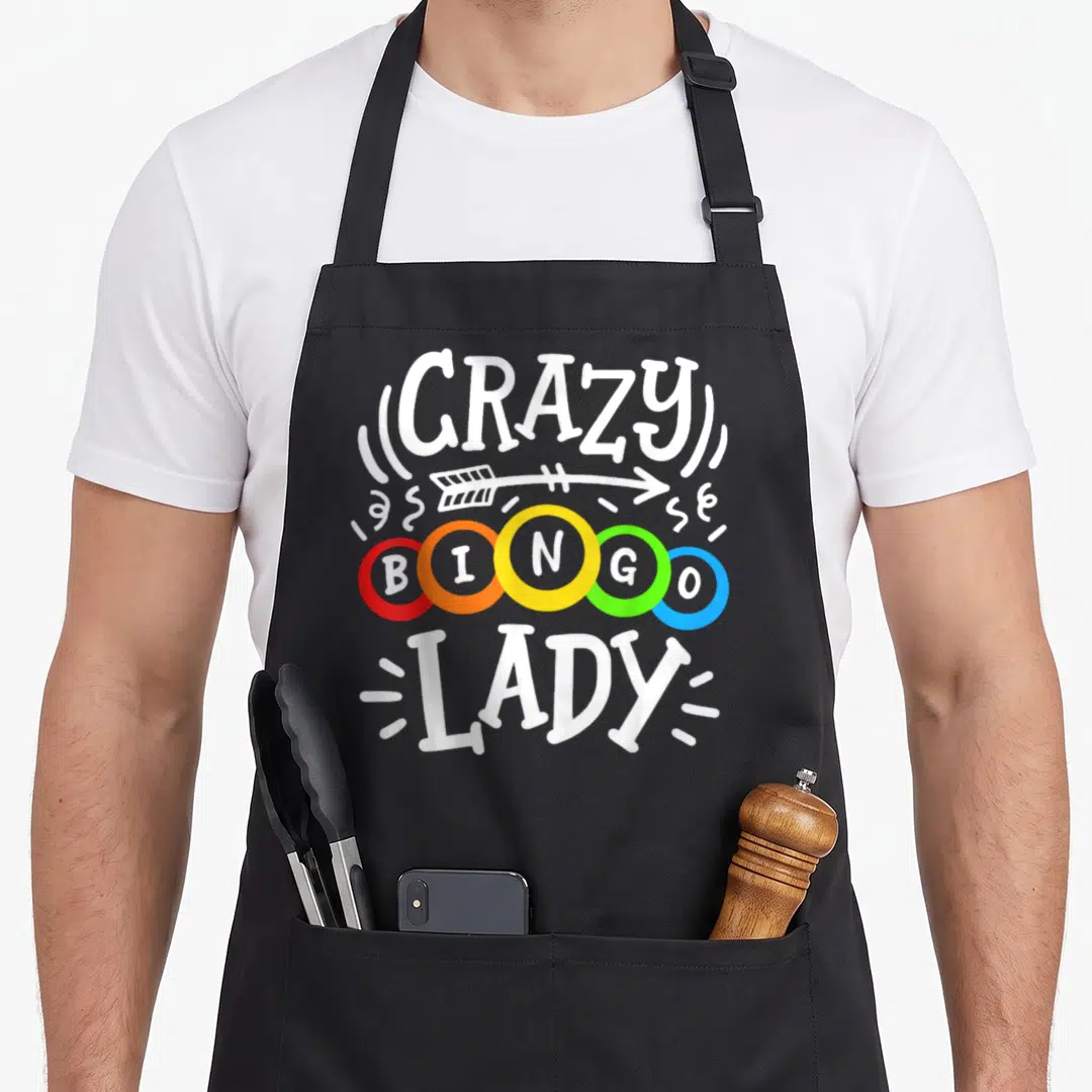 Funny bingo apron - CRAZY BINGO LADY text over five red orange yellow green blue balls with white arrow — shown on a black cotton canvas apron against a white background