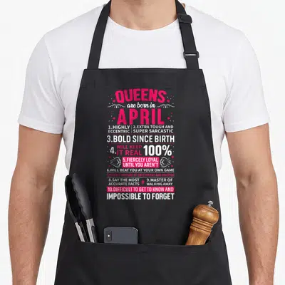 Cute queen april apron - Pink and white typography listing ten sass traits for April queens including sarcasm — shown on a black cotton canvas apron against a white background