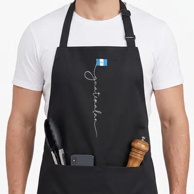 Signature guatemalan aprons - Vertical white script forming a flagpole holding a small blue and white Guatemalan flag — shown on a black cotton canvas apron against a white background