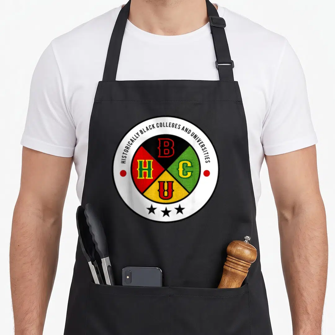 Grad african american aprons - Circular HBCU emblem with four colored quadrants containing letters B H C U and three — shown on a black cotton canvas apron against a white background