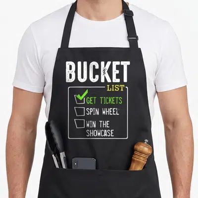Ticket bucket apron - Bucket List checklist with checked Get Tickets and Spin Wheel text in white yellow and green — shown on a black cotton canvas apron against a white background