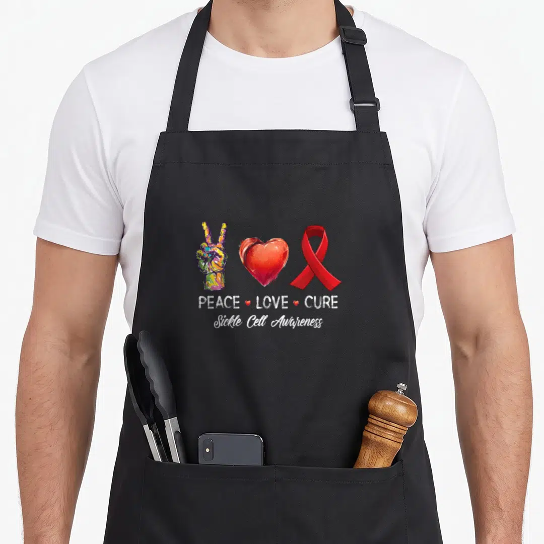Cure sickle cell awareness apron - Peace hand heart and red ribbon with PEACE LOVE CURE text and Sickle Cell Awareness — shown on a black cotton canvas apron against a white background