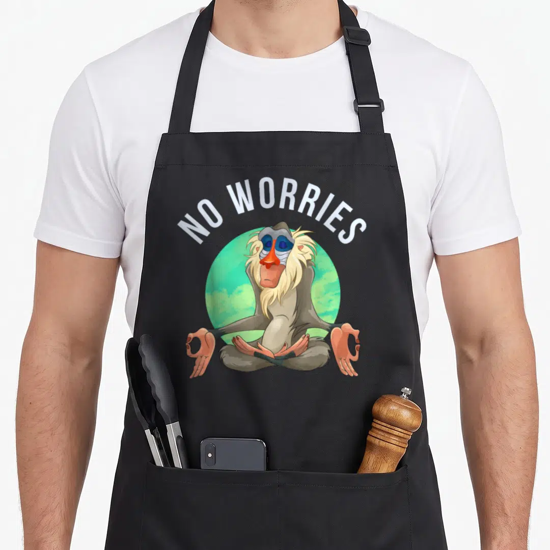 Rafiki rakia apron - Mandrill meditating in lotus pose under arched NO WORRIES text on green circle — shown on a black cotton canvas apron against a white background