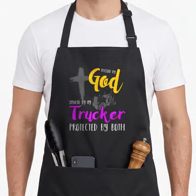 Pampered blessed god apron - Grey cross and truck graphic with stacked yellow magenta white text reading Blessed by God — shown on a black cotton canvas apron against a white background
