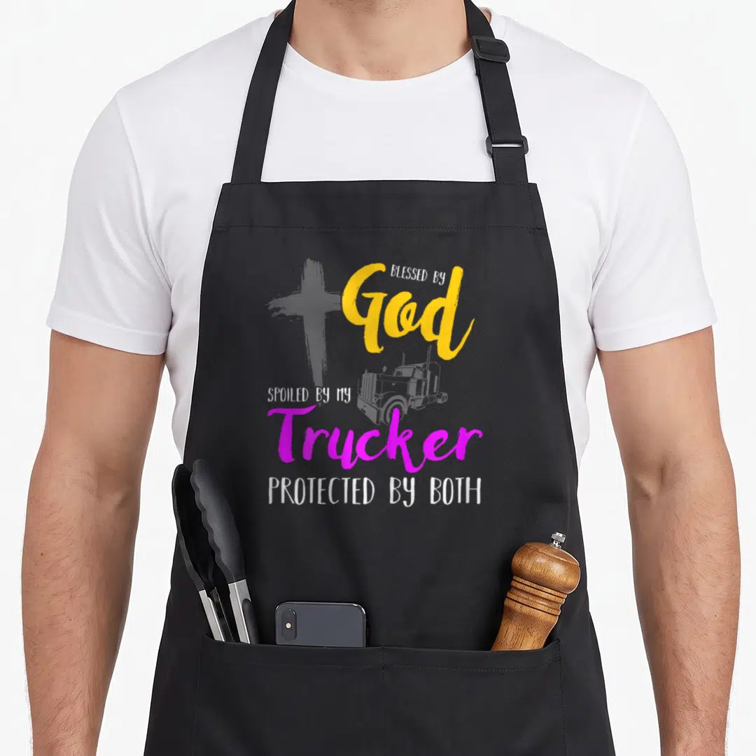 Pampered blessed god apron - Grey cross and truck graphic with stacked yellow magenta white text reading Blessed by God — shown on a black cotton canvas apron against a white background