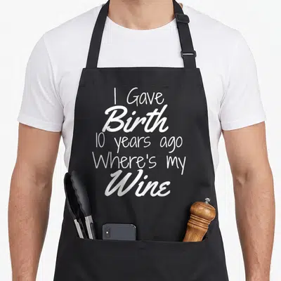 Birthday wine aprons - White text I Gave Birth 10 years ago Where's my Wine on black fabric — shown on a black cotton canvas apron against a white background