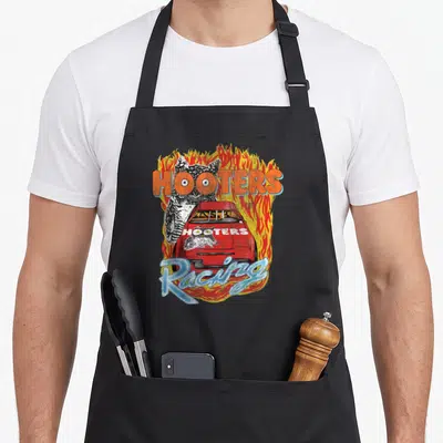 Hooter racing apron - Red race car with two owls, HOOTERS text, flames, Racing script in orange red yellow light blue — shown on a black cotton canvas apron against a white background