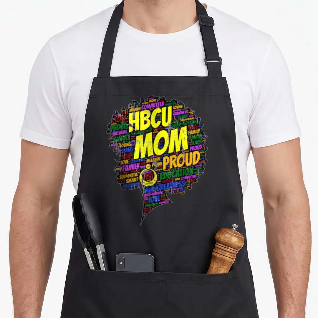 Hbcu graduation apron - HBCU MOM PROUD yellow text over colorful word cloud woman silhouette — shown on a black cotton canvas apron against a white background