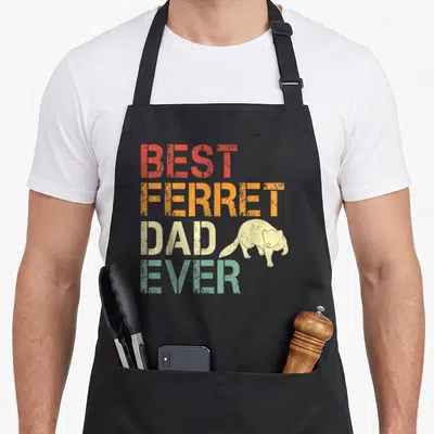 Animal ferret dad apron - Stacked BEST FERRET DAD EVER text in red orange beige teal with beige ferret illustration — shown on a black cotton canvas apron against a white background