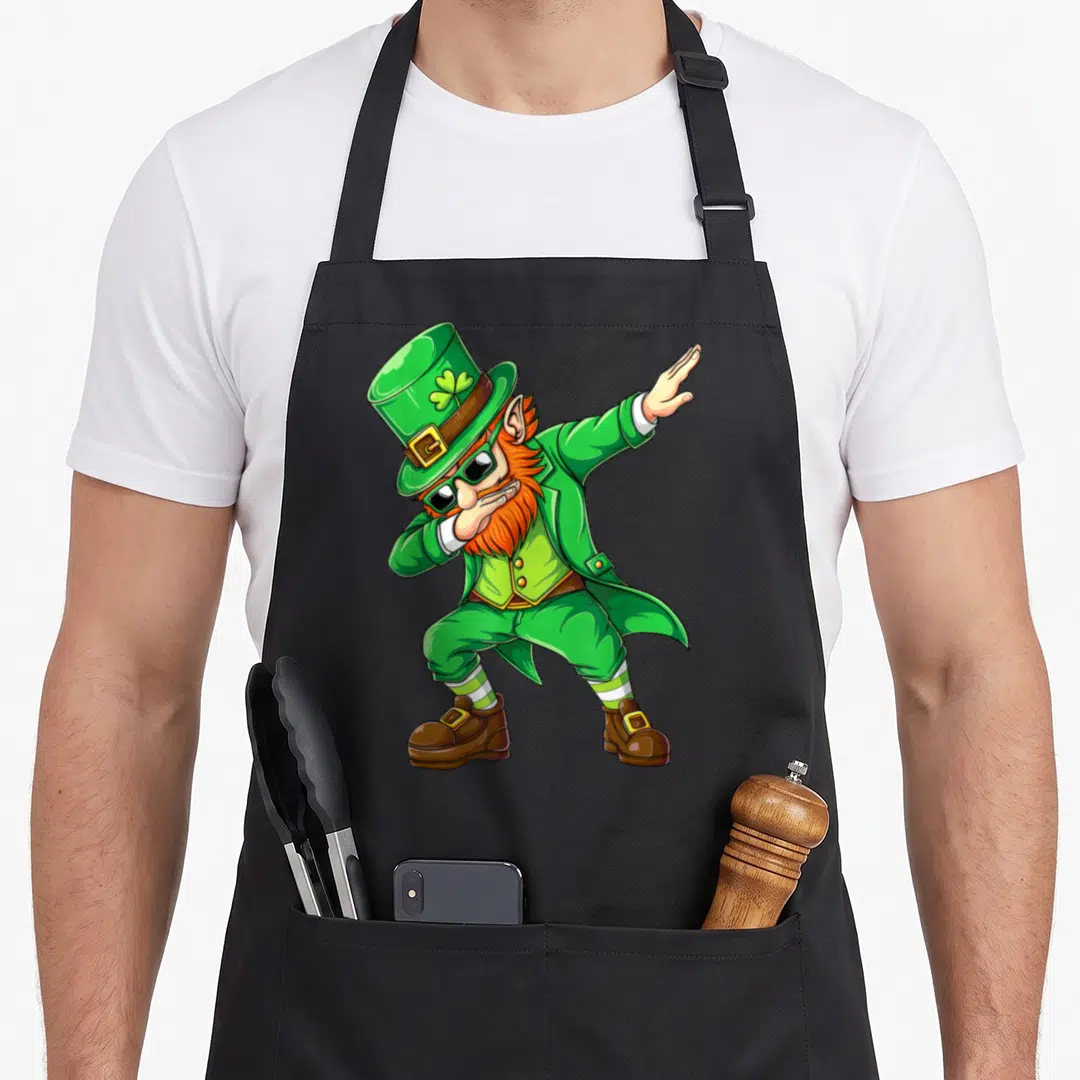 Dabbing leprechaun st patrick day aprons - Cartoon leprechaun with orange beard, sunglasses, green outfit, dabbing — shown on a black cotton canvas apron against a white background