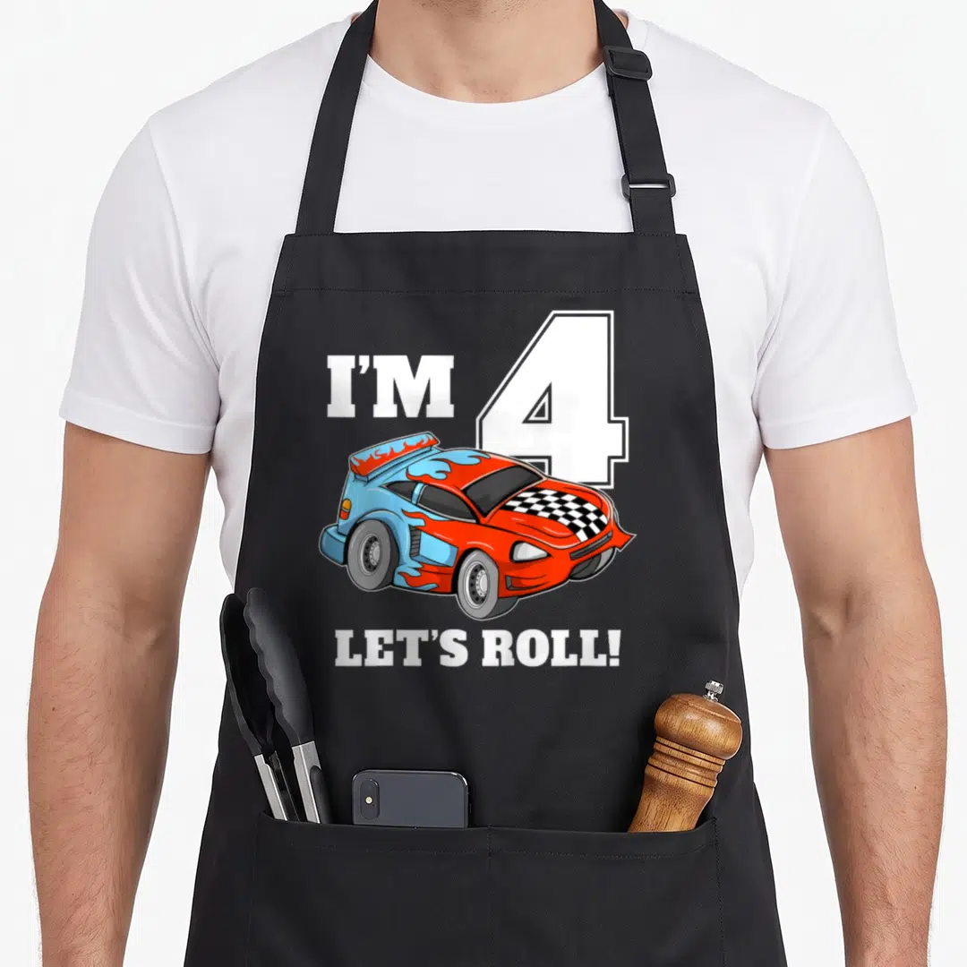 Four car apron - I'M 4, LET'S ROLL! text above a red and blue cartoon race car with flames — shown on a black cotton canvas apron against a white background