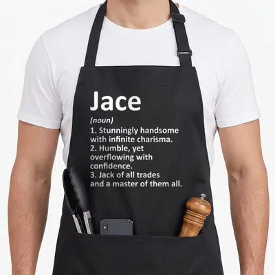Jace father day aprons - White typography defining Jace as handsome, humble, and a jack of all trades on a gray — shown on a black cotton canvas apron against a white background
