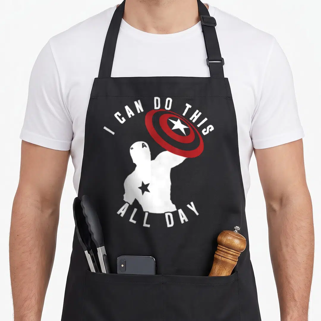 Silhouette captain apron - White silhouette figure holding red shield with arched text I Can Do This All Day — shown on a black cotton canvas apron against a white background