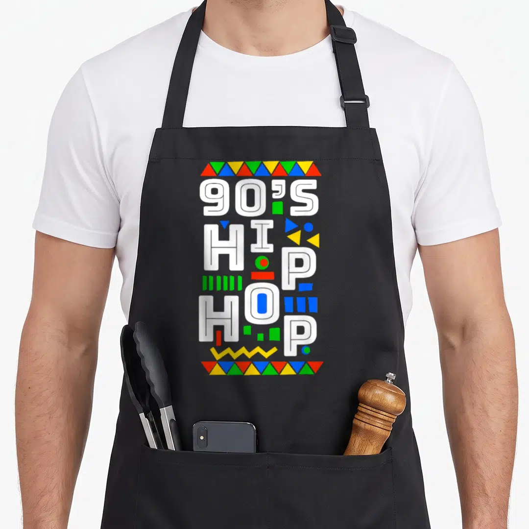 90s hip aprons - Stacked white 90S HIP HOP text with colorful triangle borders and scattered geometric shapes on black — shown on a black cotton canvas apron against a white background