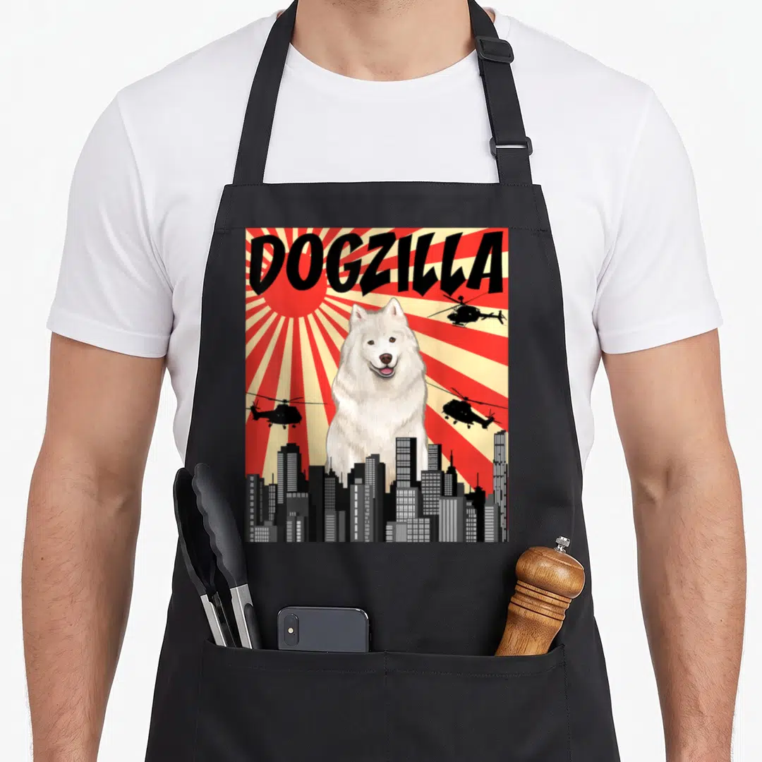 Japanese samoyed apron - DOGZILLA text above giant white dog behind city skyline with flying helicopters on red — shown on a black cotton canvas apron against a white background