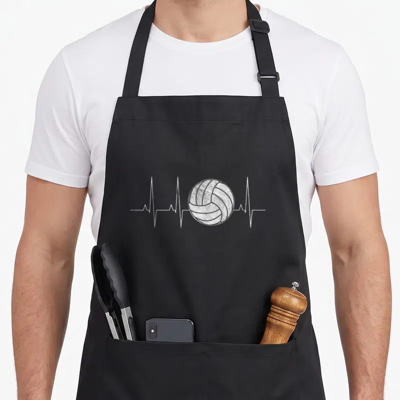 Volleyball a's aprons - White volleyball on grey heartbeat line with distressed texture — shown on a black cotton canvas apron against a white background