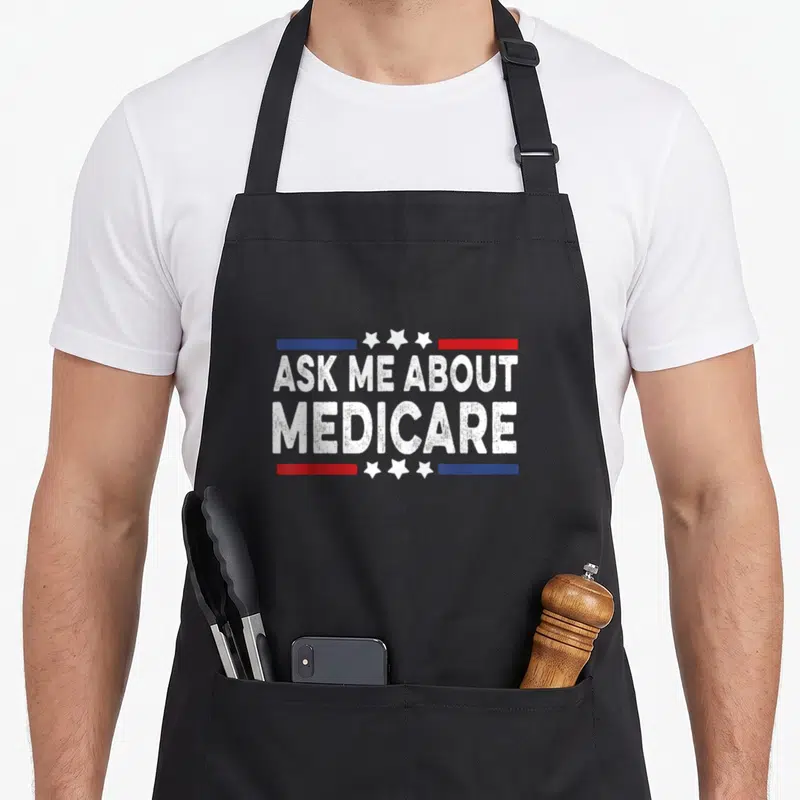 Health ask about apron - Distressed white ASK ME ABOUT MEDICARE text with red blue bars and three stars — shown on a black cotton canvas apron against a white background