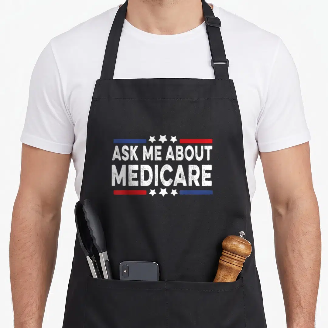 Health ask about apron - Distressed white ASK ME ABOUT MEDICARE text with red blue bars and three stars — shown on a black cotton canvas apron against a white background