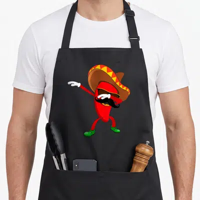 Dabbing chili pepper apron - Red cartoon chili wearing brown sombrero yellow trim green shoes black mustache sunglasses — shown on a black cotton canvas apron against a white background