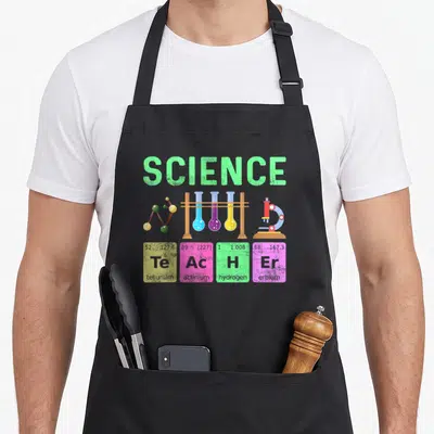 Typography teacher apron - SCIENCE text above test tubes and four element squares spelling TEACHER in green blue purple — shown on a black cotton canvas apron against a white background