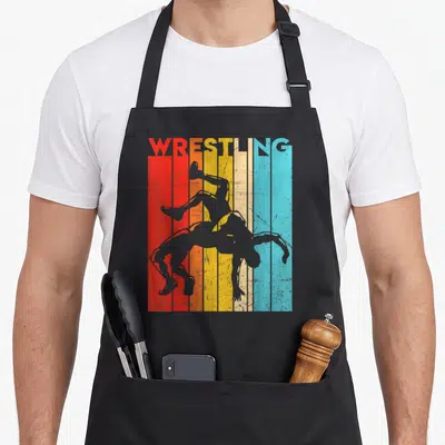 Player wrestling apron - WRESTLING text over six colored stripes with two grey wrestler silhouettes — shown on a black cotton canvas apron against a white background