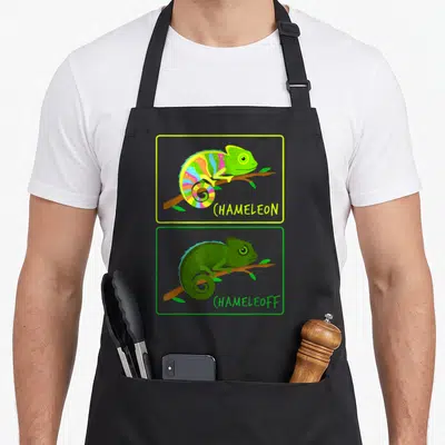 Chameleoff chameleon apron - Cartoon rainbow and green chameleons on branches with text CHAMELEON and CHAMELEOFF below — shown on a black cotton canvas apron against a white background