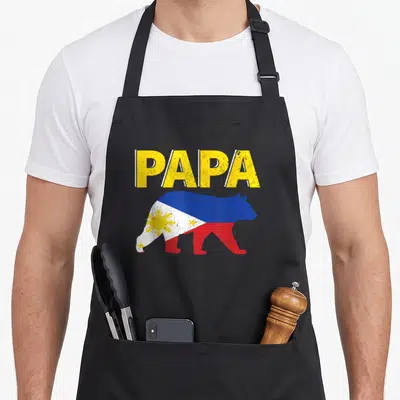 Philippine bear apron - PAPA text above bear silhouette filled with Philippine flag colors and sun symbol — shown on a black cotton canvas apron against a white background