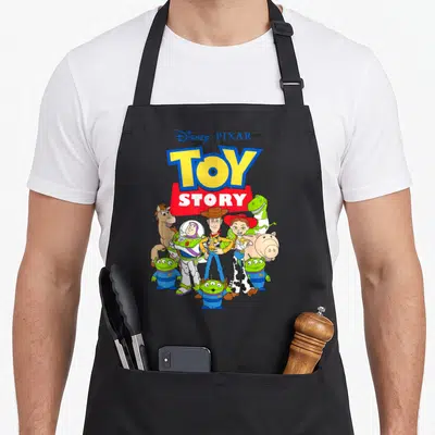 Buzz dog breed aprons - Toy Story characters clustered under logo in blue yellow red green cartoon style — shown on a black cotton canvas apron against a white background
