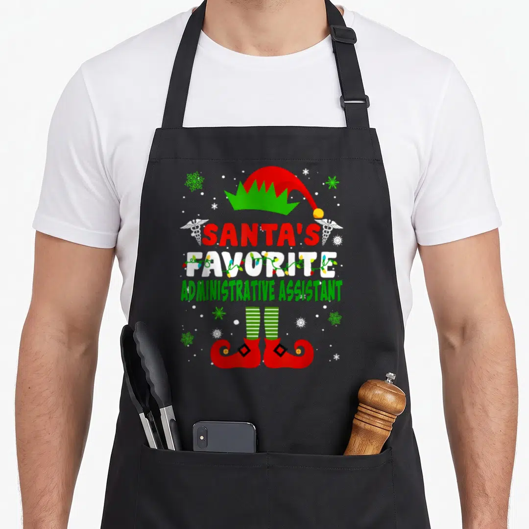 Assistant christmas apron - Santa's Favorite Administrative Assistant text with elf hat shoes caduceus and snowflakes — shown on a black cotton canvas apron against a white background