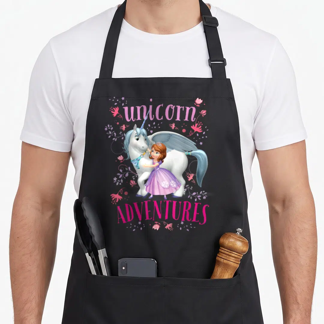 Sofia unicorn apron - Winged unicorn and girl in purple dress with pink flowers and purple vines under arched unicorn — shown on a black cotton canvas apron against a white background