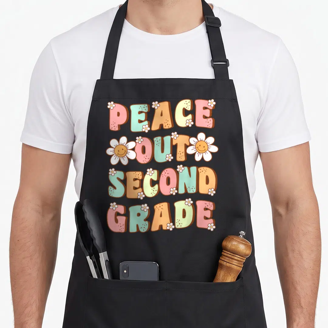 Peace second 2nd apron - Stacked colorful text reading PEACE OUT SECOND GRADE with white daisies in retro cartoon style — shown on a black cotton canvas apron against a white background