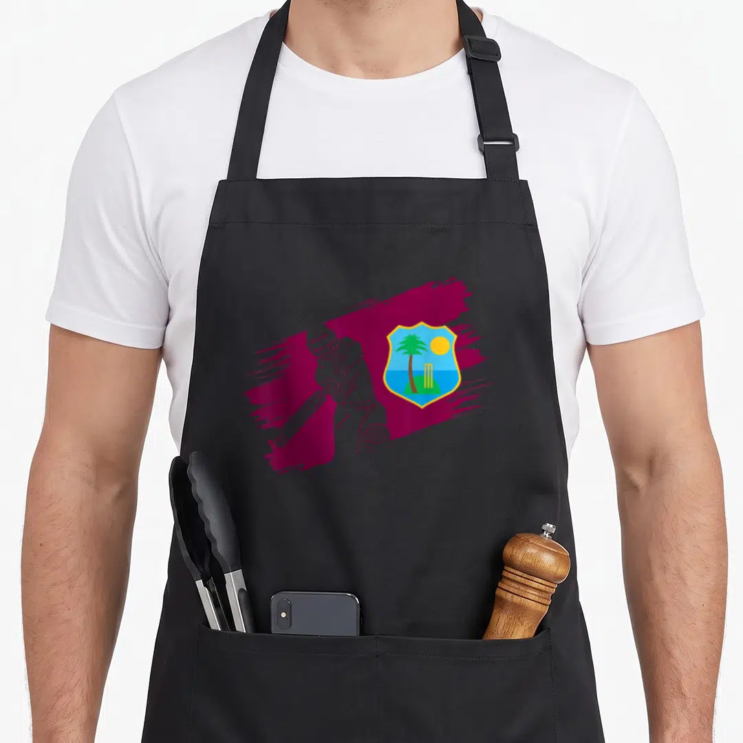 West cricket apron - White line-art cricketer over maroon stroke next to tropical shield with palm tree and stumps — shown on a black cotton canvas apron against a white background