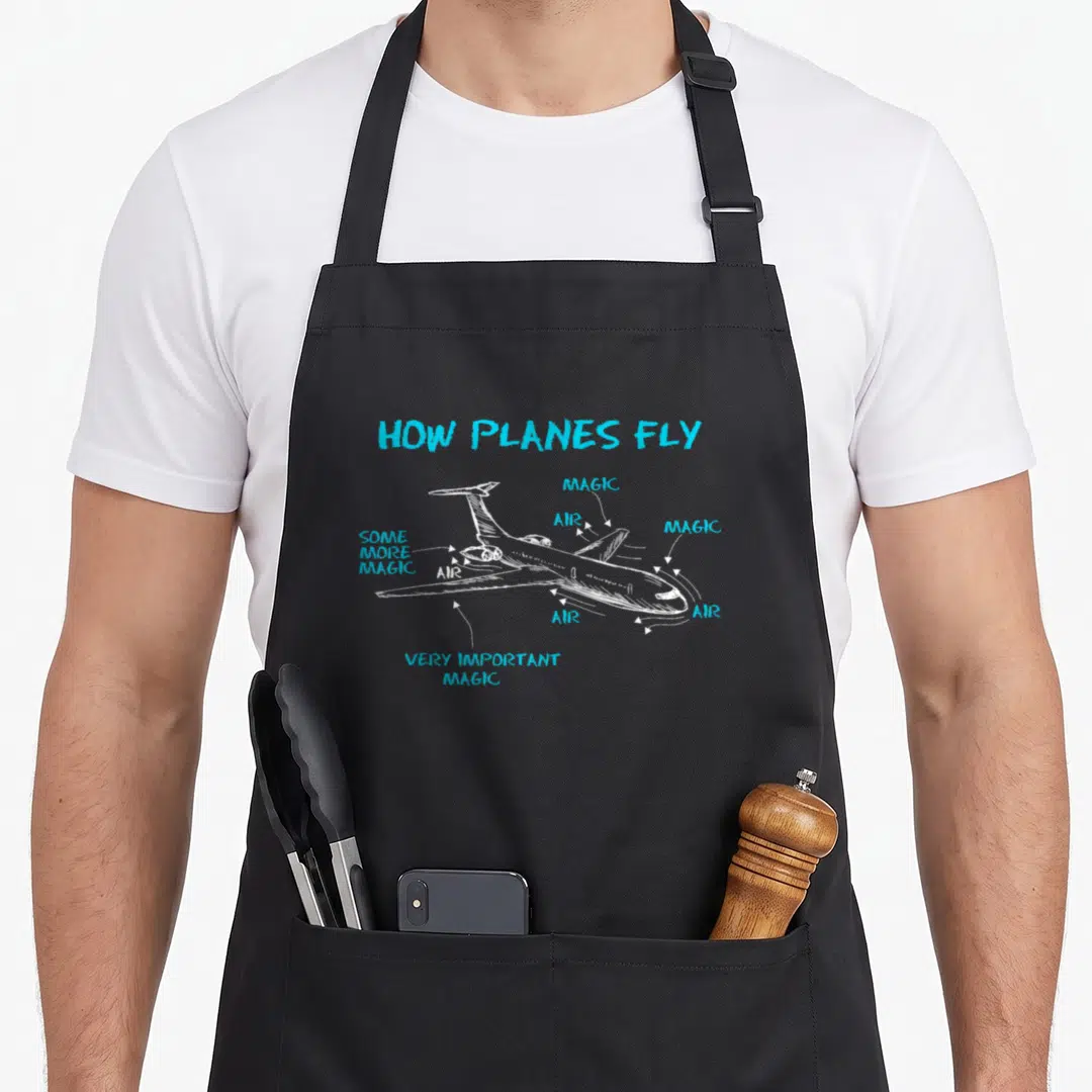 Plane engineer apron - How Planes Fly diagram with magic and air labels on white airplane sketch — shown on a black cotton canvas apron against a white background