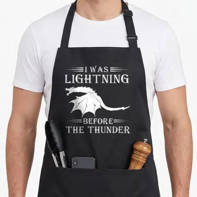 Thunder dragon apron - White dragon silhouette between text I was lightning before the thunder — shown on a black cotton canvas apron against a white background