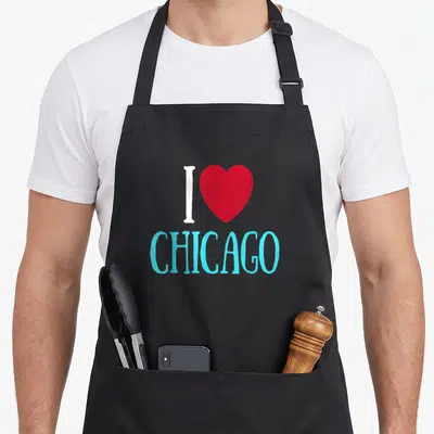 Illinois state chicago apron - White letter I, red heart, and light blue word Chicago printed on black fabric — shown on a black cotton canvas apron against a white background