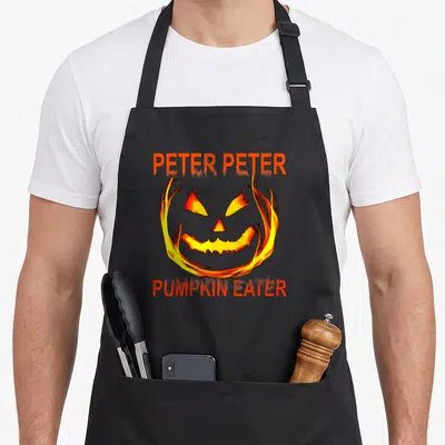 Couple costume halloween apron - Flaming cartoon jack-o-lantern face with Peter Peter Pumpkin Eater text in orange — shown on a black cotton canvas apron against a white background