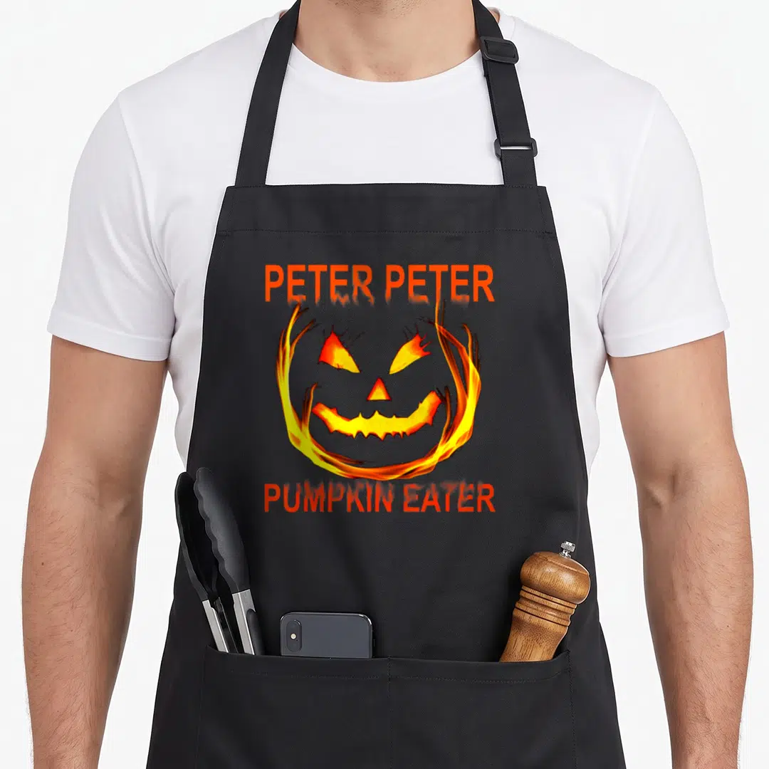 Couple costume halloween apron - Flaming cartoon jack-o-lantern face with Peter Peter Pumpkin Eater text in orange — shown on a black cotton canvas apron against a white background