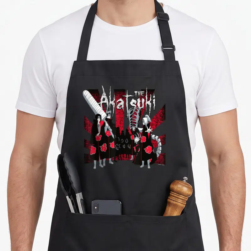 Funny shippuden akatsuki apron - The Akatsuki text above cloak characters and sword on red and white sunburst — shown on a black cotton canvas apron against a white background
